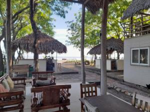 a patio with tables and chairs and straw umbrellas at Popoyo Surfcamp in Popoyo