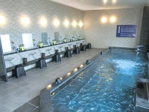 a large swimming pool in a bathroom with sinks and toilets at Natural Hot Spring Hotel Livemax Premium Hiroshima in Hiroshima