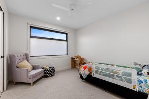 a bedroom with a bed and a chair and a window at Sensational 4 Bedroom House - Free Parking - Free WIFI in Ocean Grove