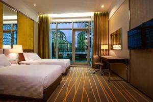 a hotel room with two beds and a desk and a window at Dorsett Putrajaya in Putrajaya
