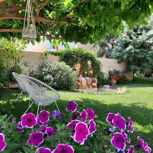 リメナリアにあるLa Verde Apartmentsの紫の花の庭園の白い椅子