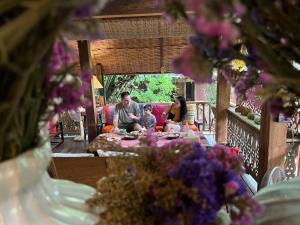 
a woman sitting at a table with flowers in a vase at Baan Boo Loo Village- SHA Plus in Chiang Mai
