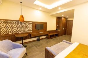 a room with a bed and a tv and a couch at Viktor Legends Hotel in Móng Cái