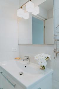 a bathroom sink with a mirror and a vase of flowers at Beachfront Bella Horizonte 4 in Savaneta