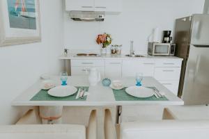 a white kitchen with a table with plates and glasses at Beachfront Bella Horizonte 4 in Savaneta