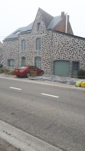 un coche rojo estacionado frente a un edificio de piedra en chez Christelle en Rochefort