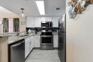 a kitchen with stainless steel appliances and white cabinets at Beachfront 2BR/2BA Atlantica Condo by Hosteeva in Myrtle Beach