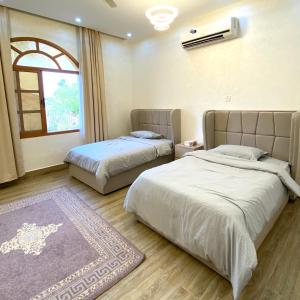 a bedroom with two beds and a window and a rug at UAE farm in Qūr