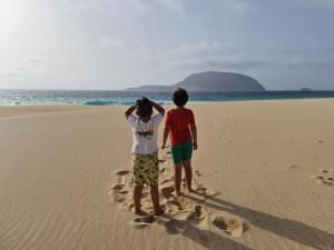 duas pessoas de pé na praia olhando para o oceano em Casa ERIZO em Caleta de Sebo