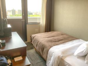 Habitación de hotel con cama, escritorio y ventana en HOTEL LiVEMAX Hiroshima Peace Park Mae en Hiroshima