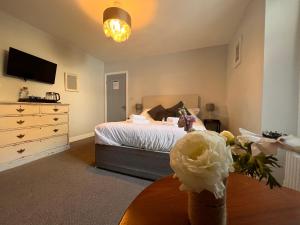 a bedroom with a bed and a dresser and a table at Selkies NQY in Newquay