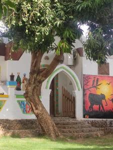 a tree in front of a building with a painting at Maghrabi's Guest house in Aswan