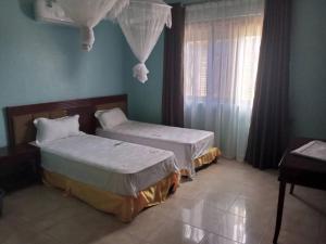 1 Schlafzimmer mit 2 Betten und einem Fenster in der Unterkunft Bucolic Heritage Resort in Adjumani