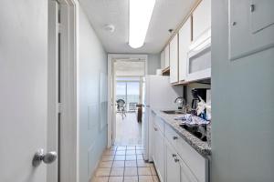a kitchen with a white refrigerator and a tile floor at Hosteeva 1BR Oceanfront Condo in Atlantica Resort near Boardwalk in Myrtle Beach
