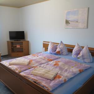 a bedroom with a large bed with pillows and a television at Ferienwohnung Kühnel in Pfaffendorf