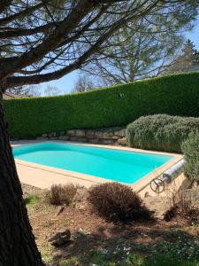 una piscina en un patio con un seto en Au fil de l’eau, en Saint-Gelais