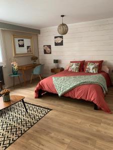 1 dormitorio con cama roja y escritorio en Au fil de l’eau, en Saint-Gelais