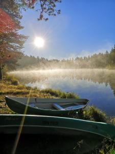 ein Boot am Ufer eines Sees mit der Sonne im Hintergrund in der Unterkunft Petäjäkylä in Kuusamo