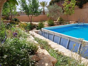 a swimming pool in a garden with flowers at Desert Rose in Midreshet Ben Gurion