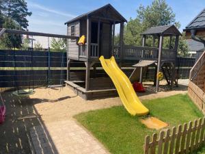 einen Spielplatz mit Rutsche und Spielhaus in der Unterkunft Domki nad jeziorem "Apartamenty Wieleń" in Wielen Zaobrzanski