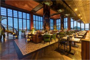 a restaurant with tables and green chairs and windows at Double - Six, Luxury Hotel - Seminyak in Seminyak