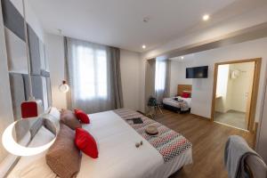 a bedroom with a large white bed with red pillows at Hôtel Méditerranée in Calvi