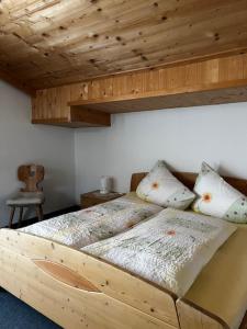 - une chambre avec un lit en bois et des oreillers dans l'établissement Ferienwohnung Gleirscher, à Neustift im Stubaital