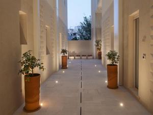 un couloir avec des plantes en pot et des lumières dans un bâtiment dans l'établissement Living u HomeSuites, à Lecce
