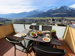 einen Tisch mit Tellern aus Essen auf einem Balkon mit Bergblick in der Unterkunft Premium apartment in Piesendorf near ski area in Piesendorf