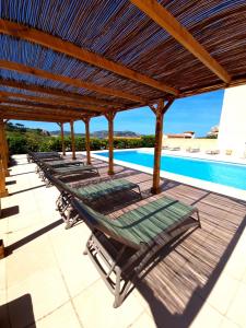 - une rangée de chaises longues sous une pergola en bois à côté de la piscine dans l'établissement Hôtel Sole Mare, à Calvi