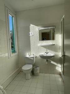 a white bathroom with a toilet and a sink at Hotel Thalassa in Cargèse