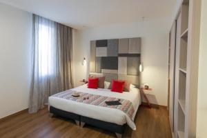 a bedroom with a large bed with red pillows at Hôtel Méditerranée in Calvi
