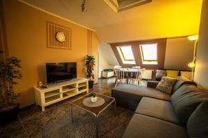 a living room with a couch and a tv at TIFFANY Apartman in Jenő