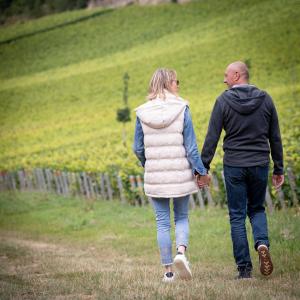 un homme et une femme qui marchent sur un champ tenant la main dans l'établissement Qualisterra - Chambres d'Hôtes, Vignoble Bio-inspirant et Bien-être Corps et Esprit, à Bar-sur-Aube