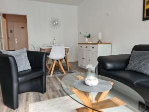 a living room with two black chairs and a table at Lütt Moor in Nordstrand