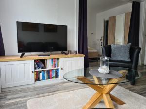 a living room with a tv and a glass table at Lütt Moor in Nordstrand