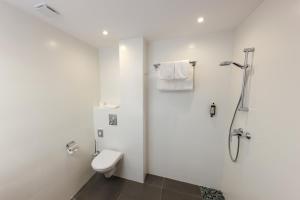 a white bathroom with a toilet and a shower at Hôtel Méditerranée in Calvi