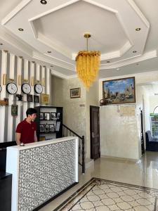 un homme debout à un comptoir dans une pièce avec des horloges dans l'établissement Mahmud Hotel, à Samarcande