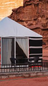 a tent with chairs in front of a cliff at Luner Camp at Wadi Rum in Wadi Rum