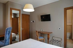 um quarto com uma mesa e cadeiras e uma televisão em BeYou Hotel Ponte Milvio em Roma