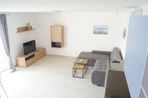 uma sala de estar com um sofá e uma televisão em Gemütliches Ferienhaus mit Whirlpool & Dachterrasse em Privlaka