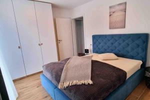um quarto com uma cama azul com um cobertor em Gemütliches Ferienhaus mit Whirlpool & Dachterrasse em Privlaka