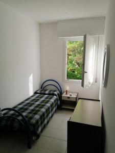 ein kleines Schlafzimmer mit einem Bett und einem Fenster in der Unterkunft Condominio Rosa in Lignano Sabbiadoro