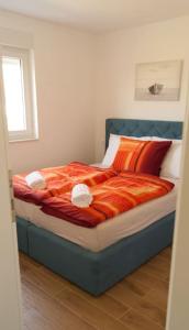 1 dormitorio con cama con sábanas de color naranja y ventana en Gemütliches Ferienhaus mit Whirlpool & Dachterrasse, en Privlaka
