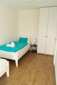 um quarto com uma cama branca e piso em madeira em Gemütliches Ferienhaus mit Whirlpool & Dachterrasse em Privlaka