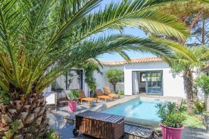 a swimming pool with palm trees and a house at Villa Lizelya in La Couarde-sur-Mer