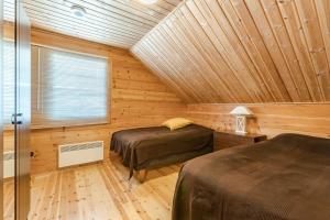 two beds in a room with a wooden ceiling at Levillas Stanssikuja 1 in Levi