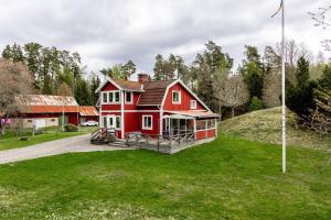 ein rotes Haus auf einem Hügel mit einem grünen Hof in der Unterkunft Holiday house with fantastic location and 300 m to its own lake shore in Rydaholm