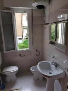 ein Bad mit einem Waschbecken, einem WC und einem Fenster in der Unterkunft Condominio Rosa in Lignano Sabbiadoro