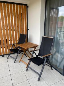 two chairs and a wooden table on a patio at Bel Mare Apartament E338 FREE PARKING in Międzyzdroje